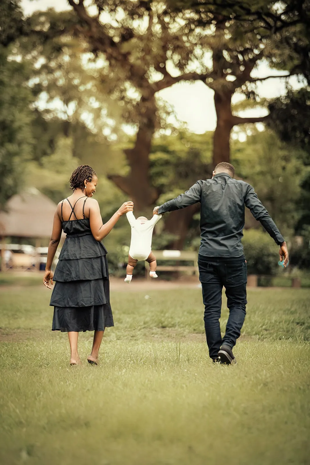 2 parents se promenant avec leur enfant dans un parc